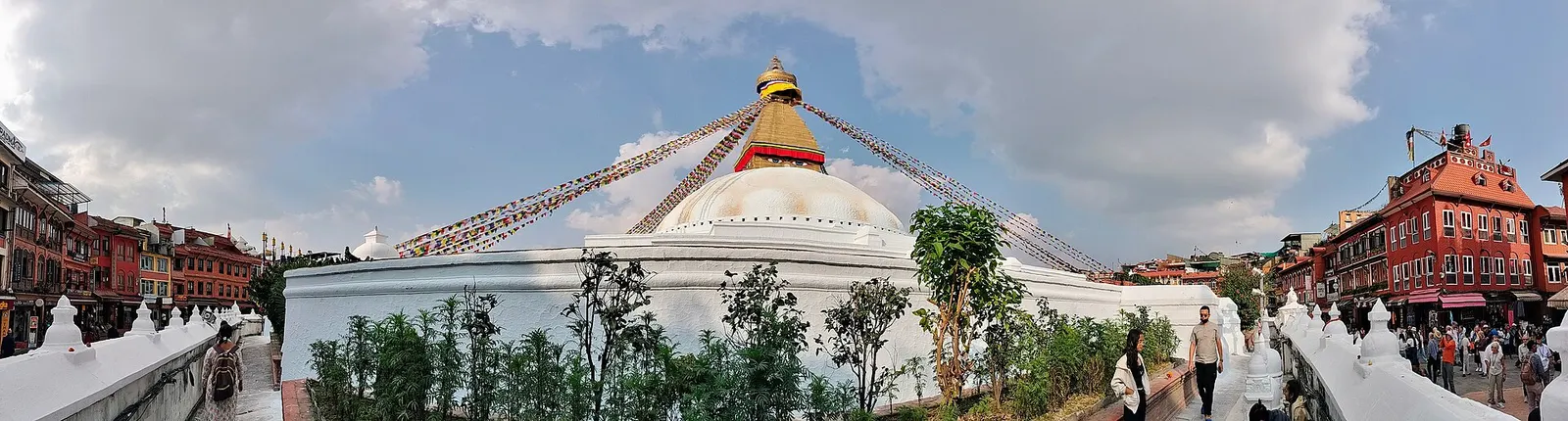 Panorama of Boudhanath stupa and the ring of buildings around its circular plaza.