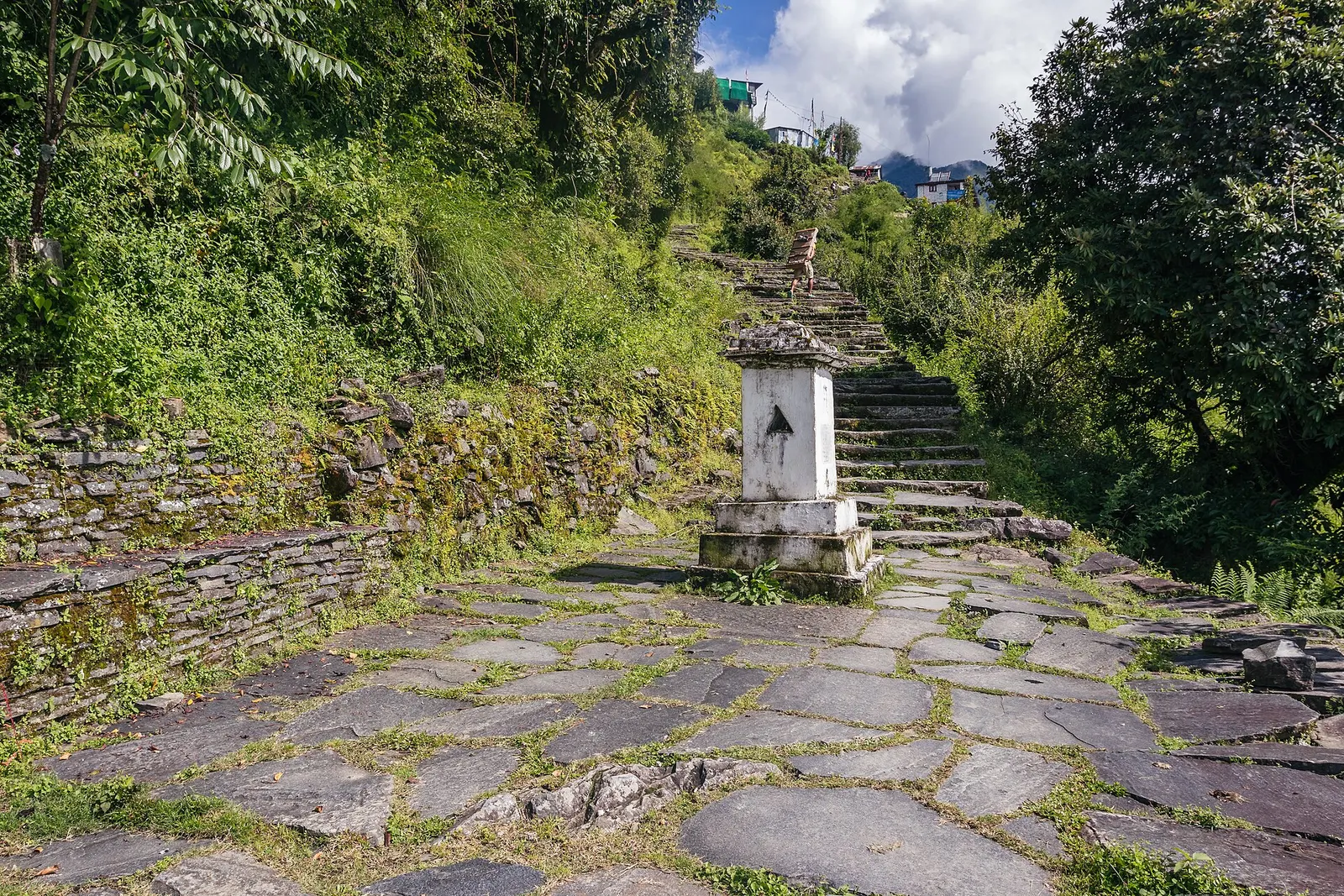 A small whitewashed chorten standing in the middle of the stone trail through Chhomrong.