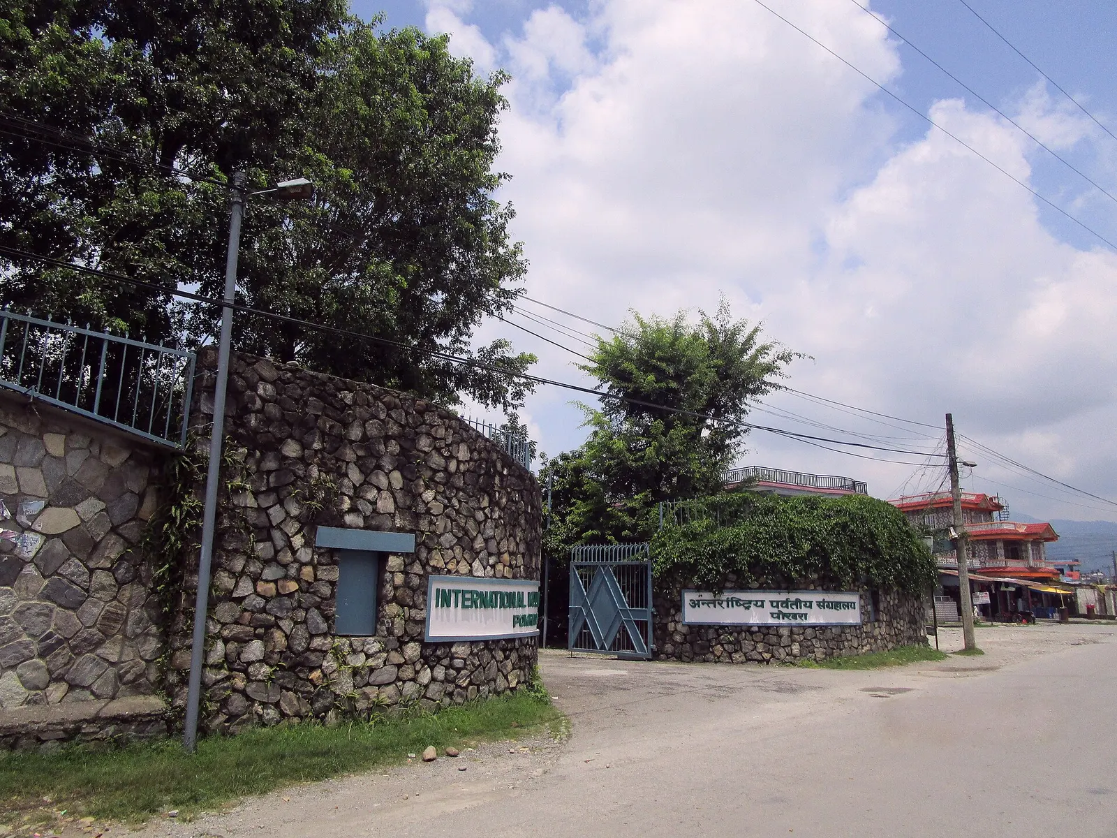 The stone entrance wall and gate of the International Mountain Museum on a quiet Pokhara road.