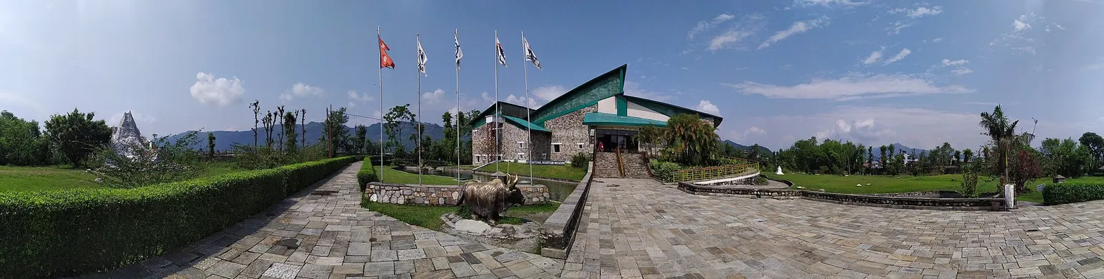 Wide view of the International Mountain Museum grounds with the main hall, flags and paved paths.
