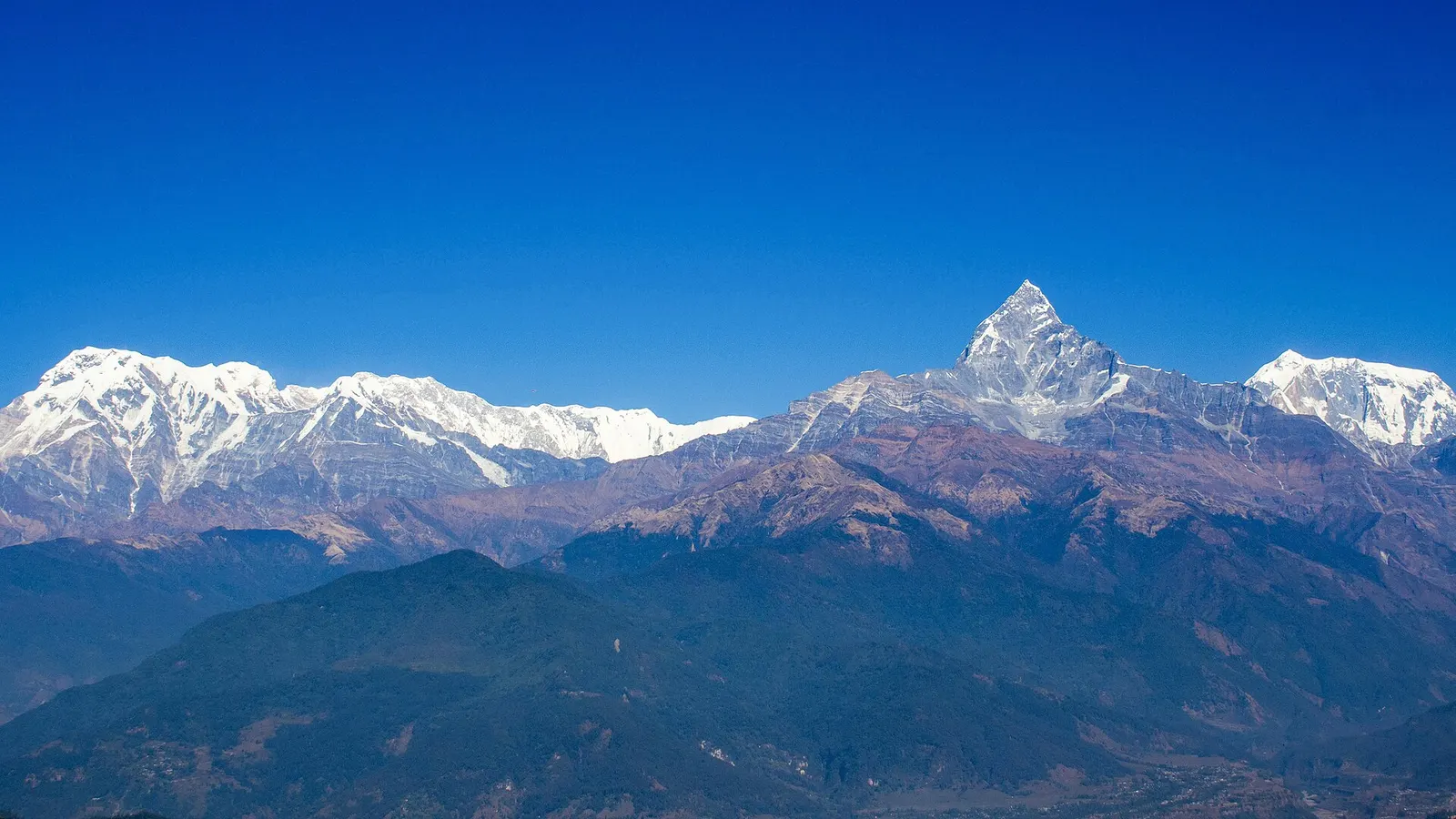 Snow peaks of Annapurna South and Machhapuchhre rising above green foothills, viewed from Sarangkot.