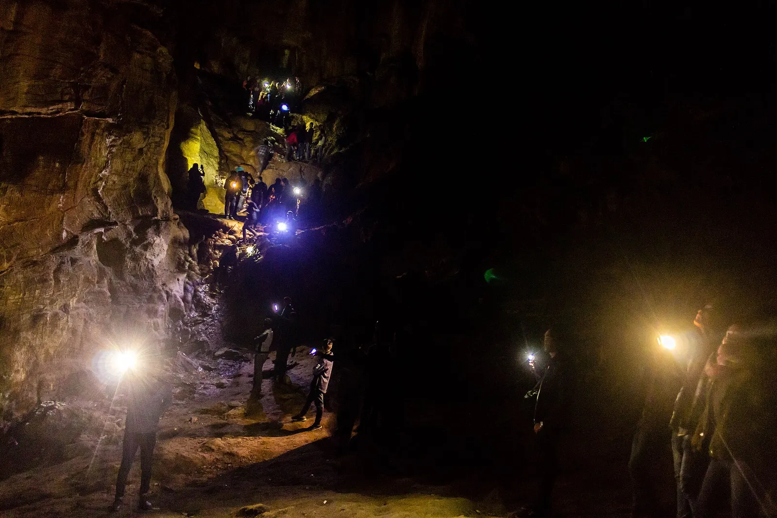 Visitors with torches making their way through the dark interior of Siddha Gufa.