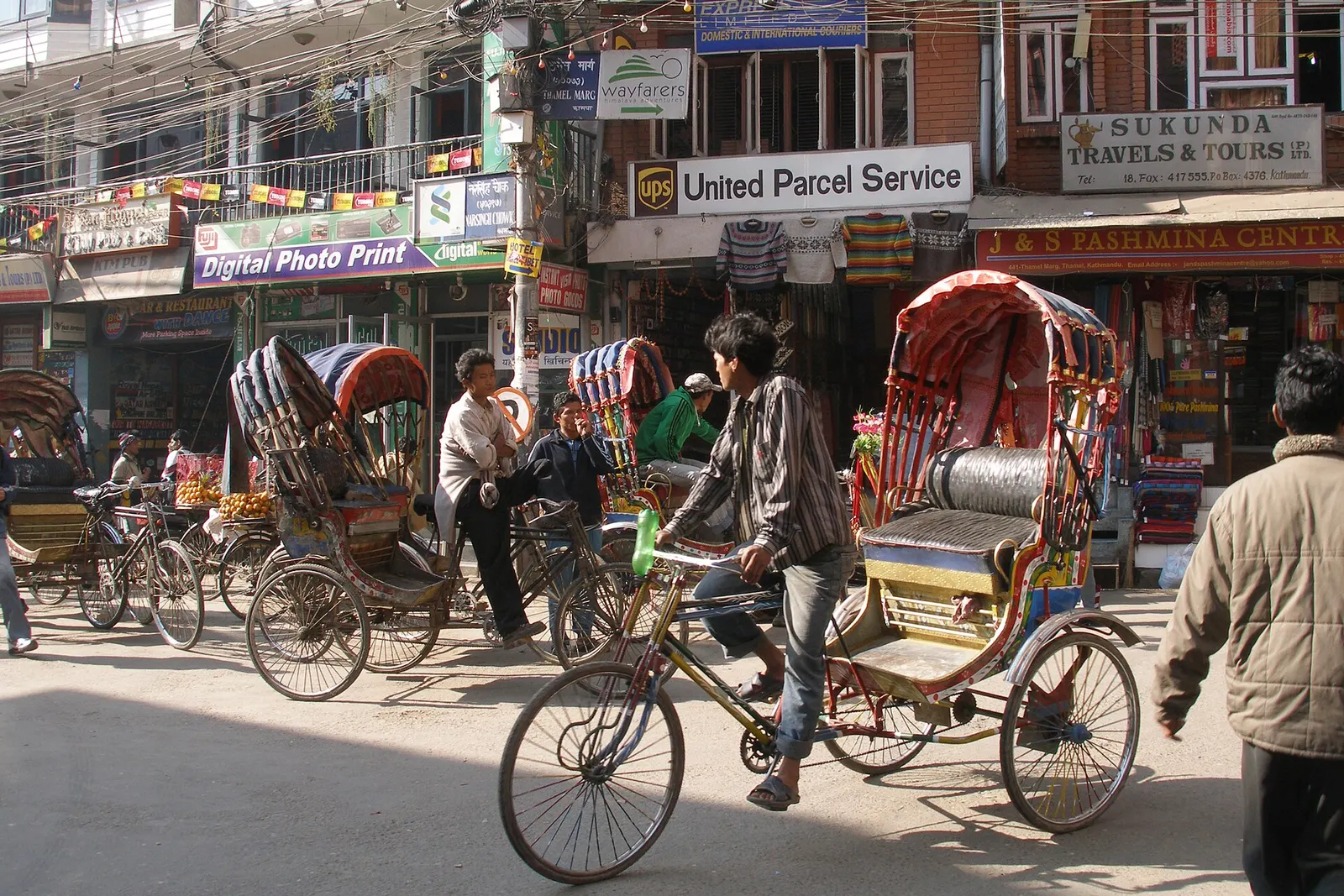 A narrow Thamel street lined with shop signs and hanging goods in Kathmandu.