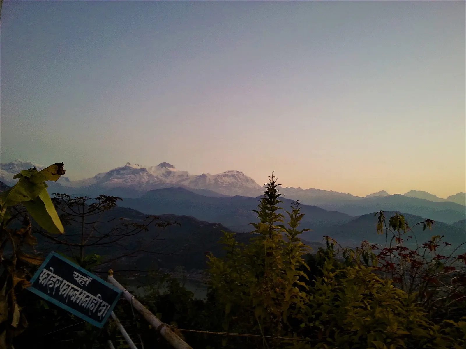 Low sun over forested ridges with snow peaks of the Annapurna range on the horizon, seen from the pagoda hill.