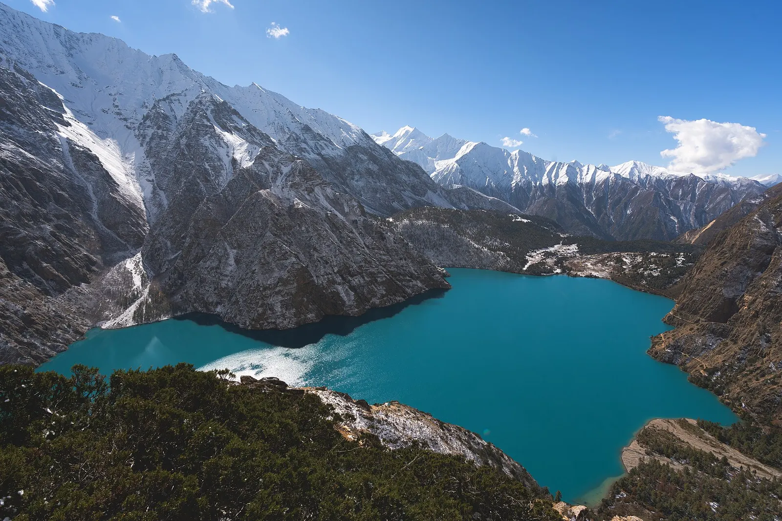 Turquoise Shey Phoksundo Lake seen from above, framed by steep rocky slopes and snowy peaks