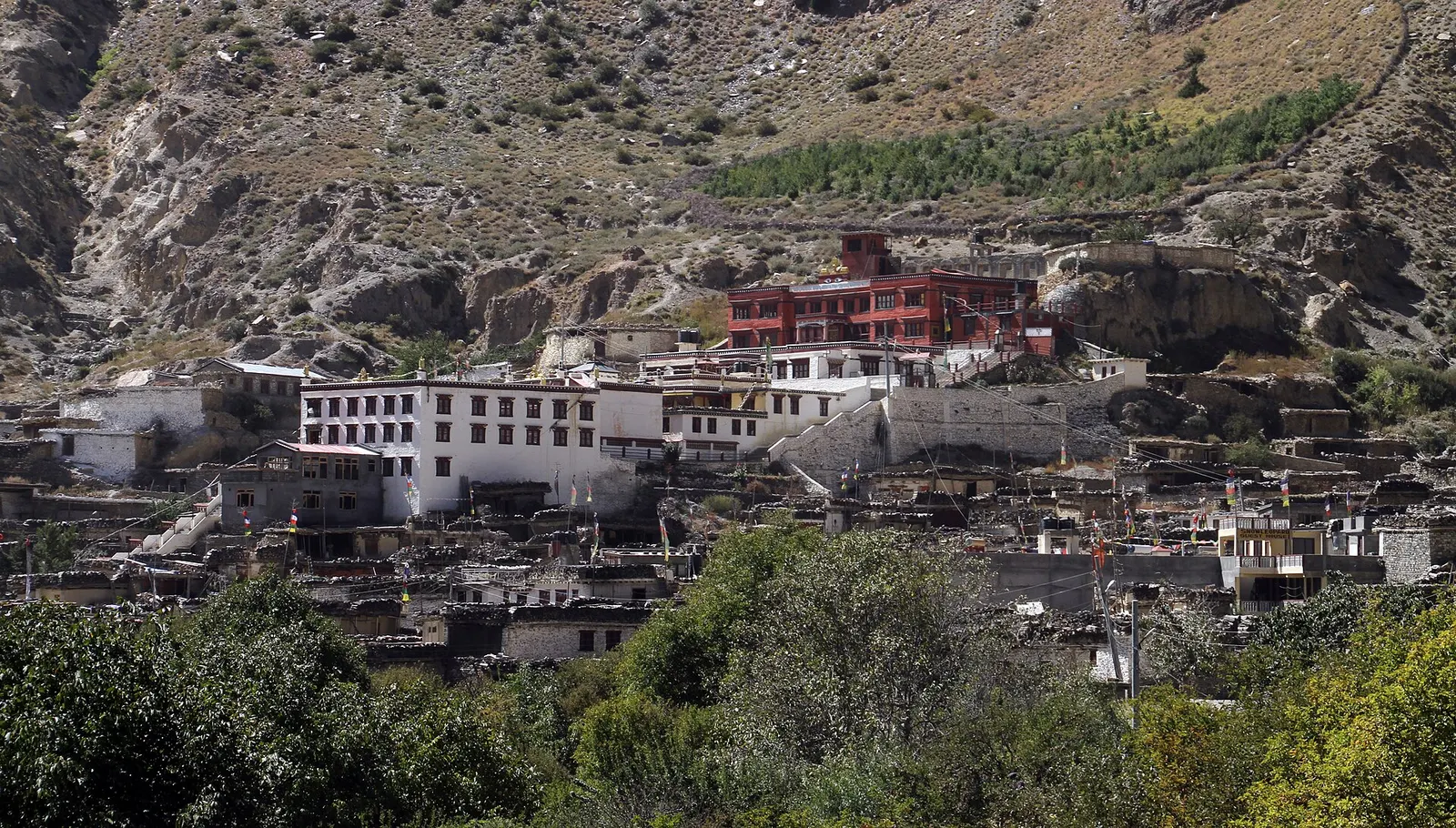 Whitewashed stone houses and a red-and-white monastery stacked on a hillside in Marpha village