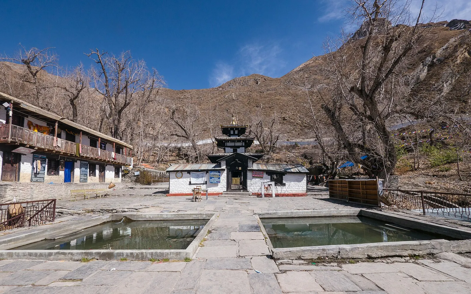 The pagoda-roofed Muktinath Temple behind its two sacred stone pools, with dry Mustang hills behind