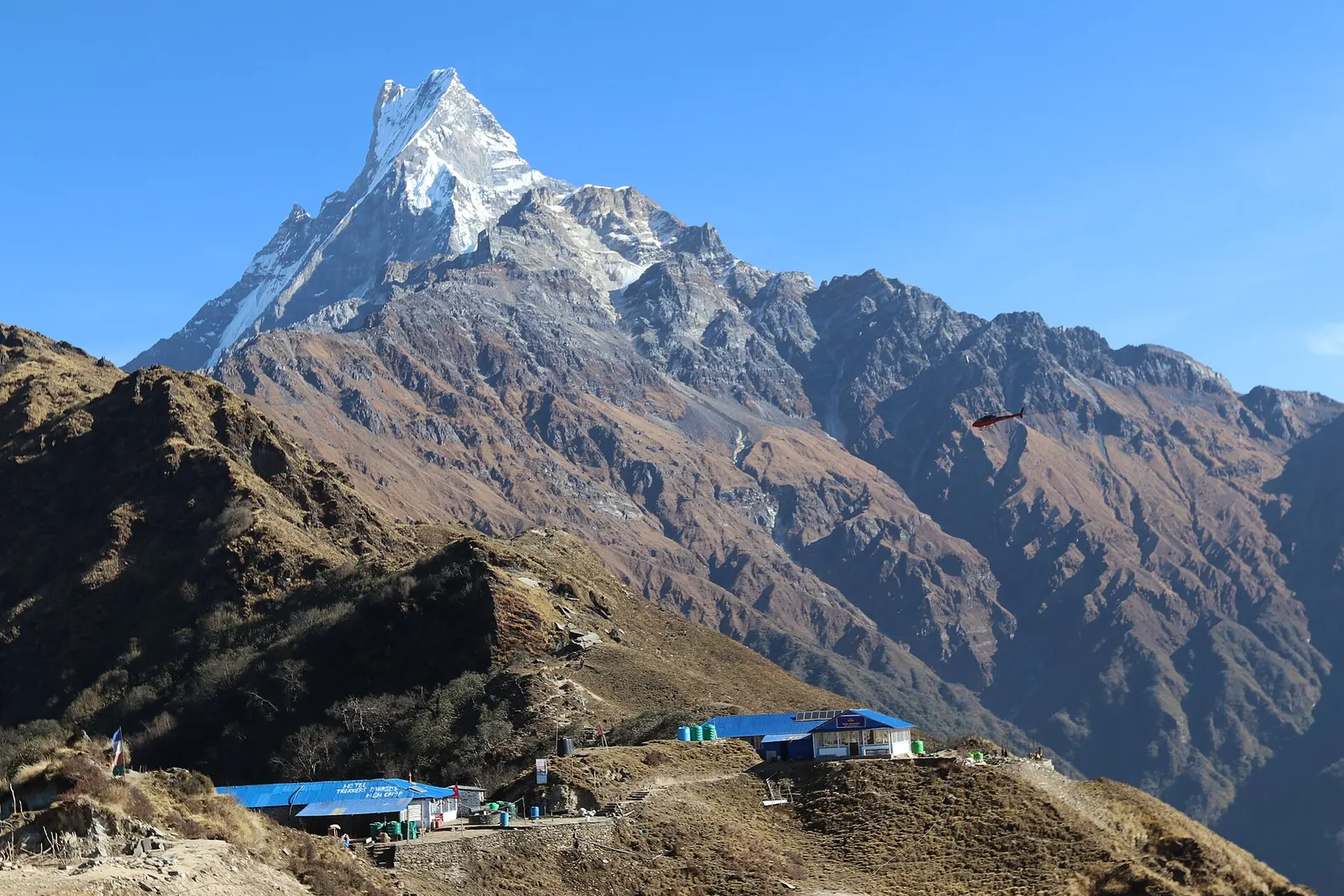Blue-roofed lodges of High Camp on the Mardi Himal ridge below Machhapuchhre.