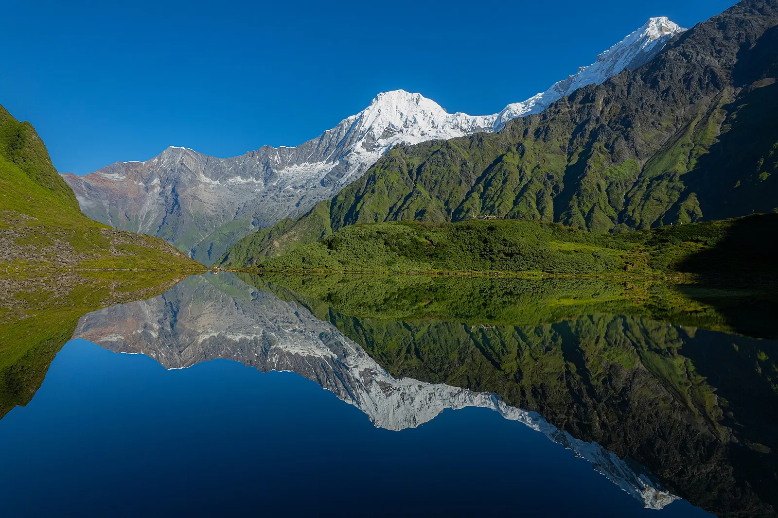 The still Kalo Daha lake in Ruby Valley reflecting the surrounding slopes.