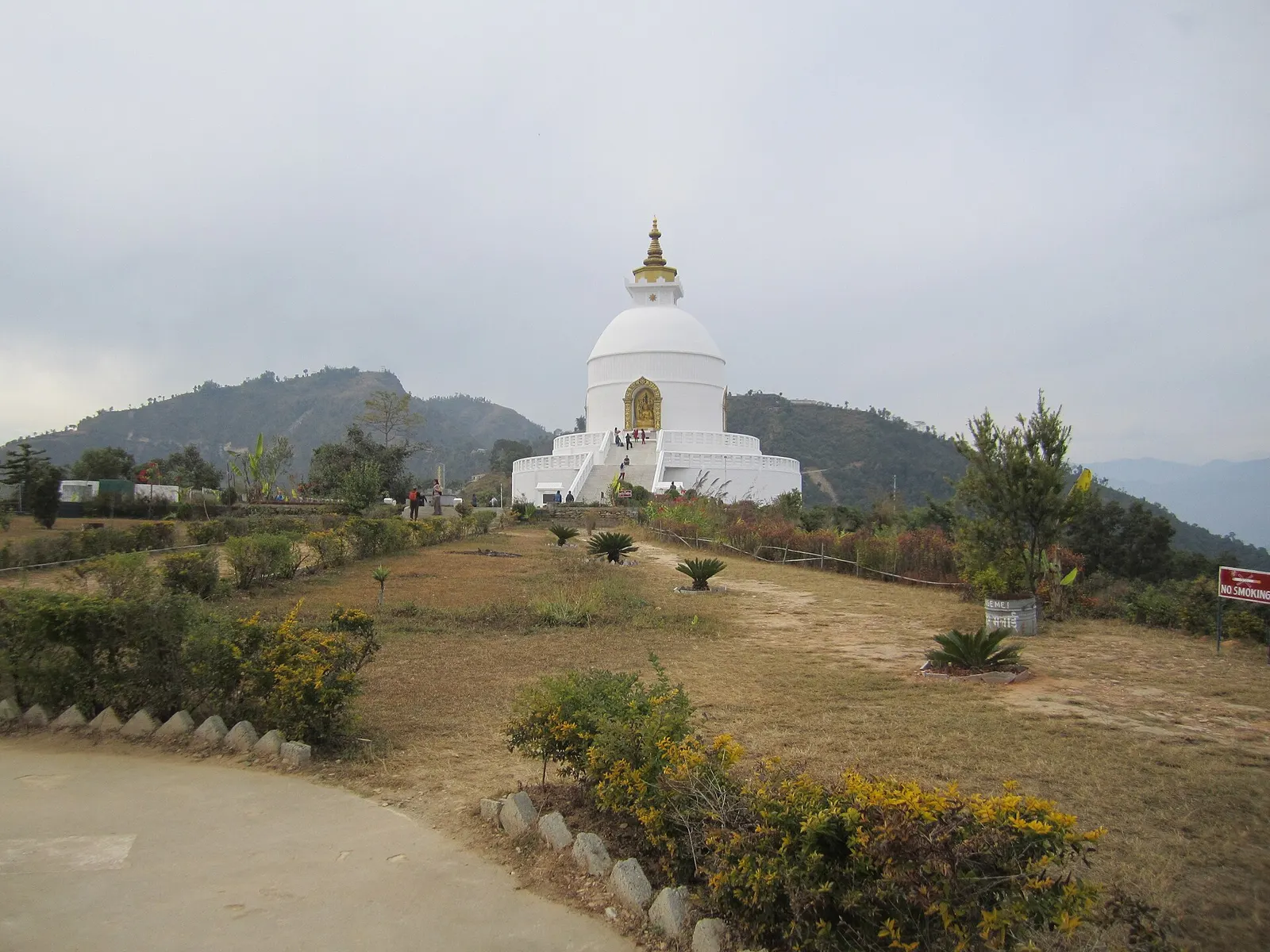 The white dome and gilded spire of the World Peace Pagoda standing above a garden path on its hilltop.