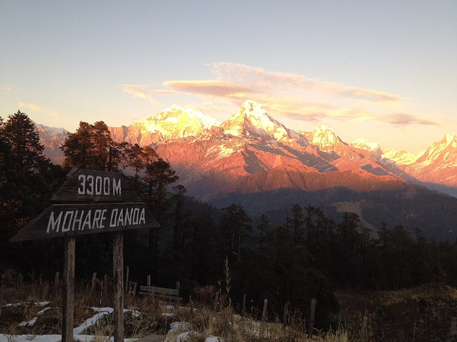 A wooden sign reading Mohare Danda 3300 m in front of the Annapurna range glowing at sunset.