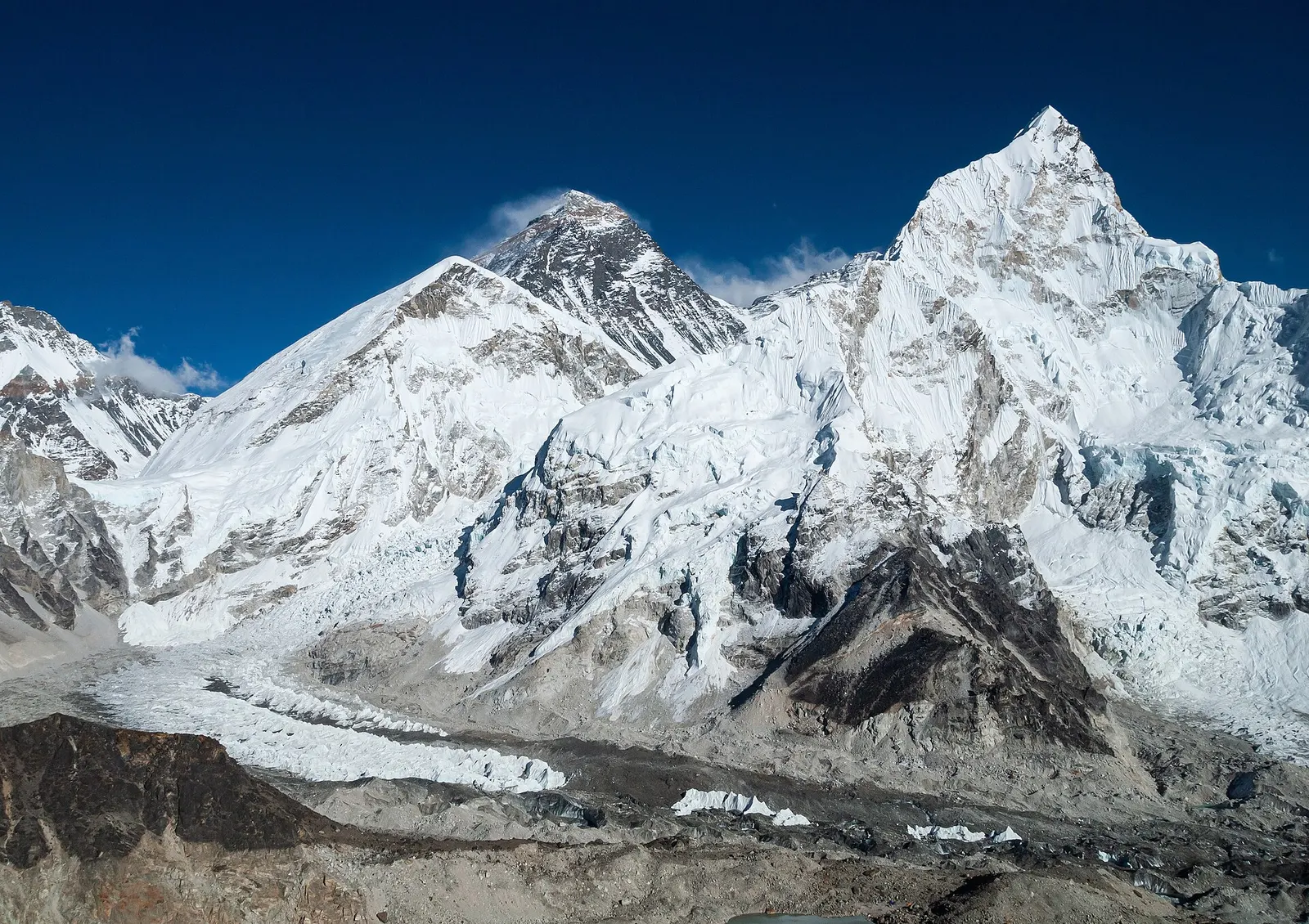 Mount Everest's dark summit pyramid beside the snowy face of Nuptse, above the rubble-covered Khumbu Glacier